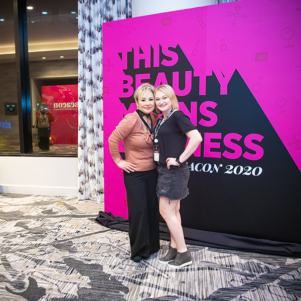 Mother daughter posing together in front of a large billboard