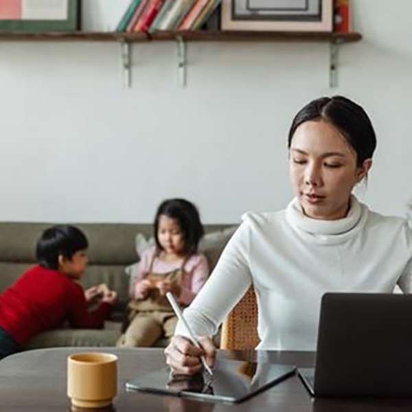 Image of a woman working with her children in the background
